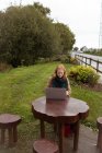 Junge Frau benutzt Laptop im Park — Stockfoto
