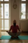 Homem realizando ioga no tapete de exercício em casa — Fotografia de Stock