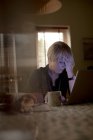 Besorgte ältere Frau benutzt Laptop im heimischen Wohnzimmer — Stockfoto