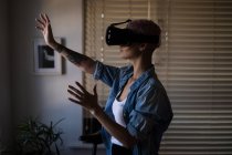 Giovane donna adulta utilizzando auricolare realtà virtuale a casa . — Foto stock