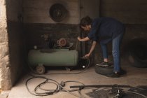 Female worker using portable spray paint machine in workshop — Stock Photo