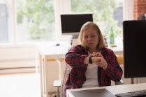 Женщина-руководитель проверяет время на своих умных часах в офисе — стоковое фото