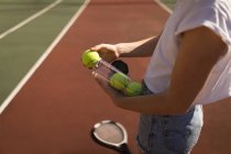 Серединна секція жінки, що знімає тенісний м'яч з футляру для тенісу — стокове фото