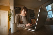Mulher usando laptop na cozinha em casa — Fotografia de Stock