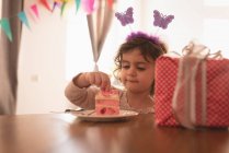 Little girl eating cake in living room at home. — Stock Photo