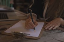 Крупный план зрелой женщины, пишущей дома на бумаге — стоковое фото