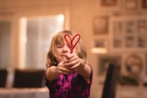 Дівчина тримає прикрасу форми серця вдома — стокове фото