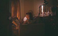 Mulher lendo um livro na sala de estar em casa — Fotografia de Stock