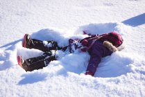 Беззаботная девушка играет в снегу зимой — стоковое фото
