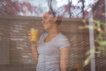 Sourire jeune femme enceinte tenant un verre de jus à la maison — Photo de stock
