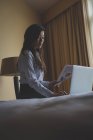 Деловая женщина с документами во время работы на ноутбуке в гостиничном номере — стоковое фото