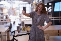 Щаслива жінка-виконавця бере селфі з мобільним телефоном в офісі — стокове фото