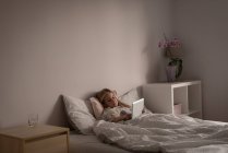 Chica usando tableta digital en el dormitorio en casa - foto de stock