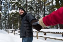 Пара тримає руки в сніжному лісі взимку — стокове фото