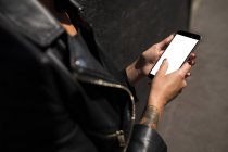 Mid section of woman in leather jacket using mobile phone. — Stock Photo