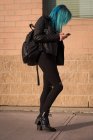 Mulher elegante com mochila usando telefone celular — Fotografia de Stock