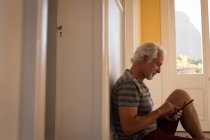 Активный пожилой человек, пользующийся цифровым планшетом дома — стоковое фото
