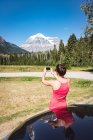 Woman taking photo with mobile phone on a sunny day — Stock Photo