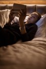 Жінка використовує цифровий планшет, розслабляючись на ліжку в готелі — стокове фото