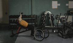 Відсталим людиною вправи з гантелями на жим лежачи в тренажерний зал — стокове фото