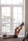 Mujer pensativa relajándose cerca de la ventana en casa - foto de stock