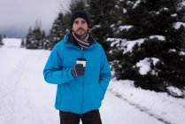Mann mit Kaffeetasse in verschneiter Landschaft im Winter. — Stockfoto