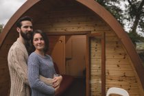 Casal afetuoso abraçando uns aos outros fora da cabine de madeira — Fotografia de Stock