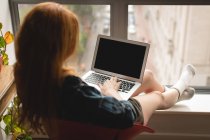 Visão traseira da mulher usando laptop em casa — Fotografia de Stock
