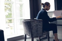 Woman using laptop at table in hotel room — Stock Photo