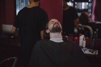 Man getting his beard shaved with trimmer at barbershop — Stock Photo