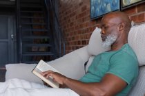 Primer plano del hombre mayor leyendo un libro en casa - foto de stock