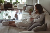 Беременная женщина отдыхает на диване в гостиной на дому — стоковое фото