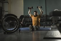 Людина з інвалідністю піднімає гантелі в спортзалі — стокове фото