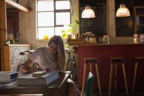 Молодая женщина пишет на книге в кафе — стоковое фото
