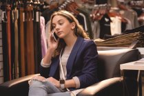 Красивая девушка разговаривает по мобильному телефону во время отдыха на диване — стоковое фото