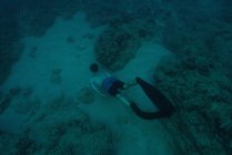 Вид сверху на человека ныряющего с аквалангом в море коралловым рифом — стоковое фото