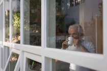 Uomo anziano che prende un caffè in cucina a casa — Foto stock