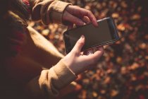 Середина жінки, що використовує мобільний телефон восени — стокове фото