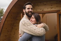 Affectionate couple embracing each other outside the log cabin — Stock Photo