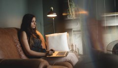 Frau benutzt Laptop auf Sofa im heimischen Wohnzimmer — Stockfoto