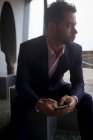 Homme d'affaires réfléchi utilisant le téléphone portable dans la chambre d'hôtel — Photo de stock