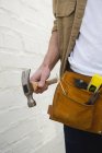 Seção média de carpinteiro masculino com cinto de ferramentas segurando martelo — Fotografia de Stock