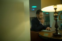Homme d'affaires utilisant un ordinateur portable dans la chambre d'hôtel — Photo de stock