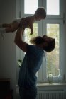 Pai brincando com seu bebê em casa — Fotografia de Stock