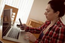 Woman using mobile phone and laptop at home. — Stock Photo