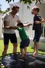 Батько грає зі своїми синами в саду в сонячний день — стокове фото