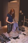 Женщина складывает одежду в спальне дома — стоковое фото