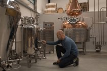 Работник мужского пола контролирует манометр резервуара на пивоваренном заводе — стоковое фото