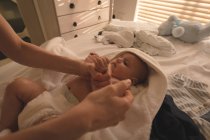 Bebê bonito deitado na cama e mãe brincando com ele na cama em casa — Fotografia de Stock