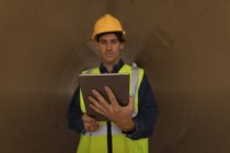 Aufmerksame männliche Arbeiter mit digitalem Tablet in einem Betontunnel — Stockfoto